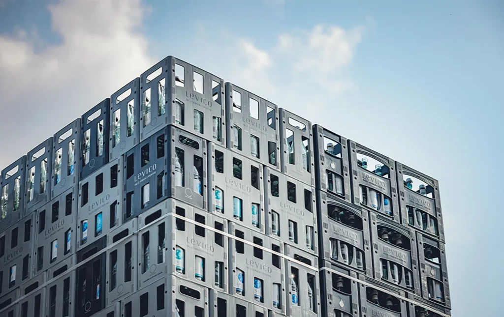 Un moderno edificio con facciata a griglia scura e finestre, visto dal basso verso un cielo parzialmente nuvoloso.