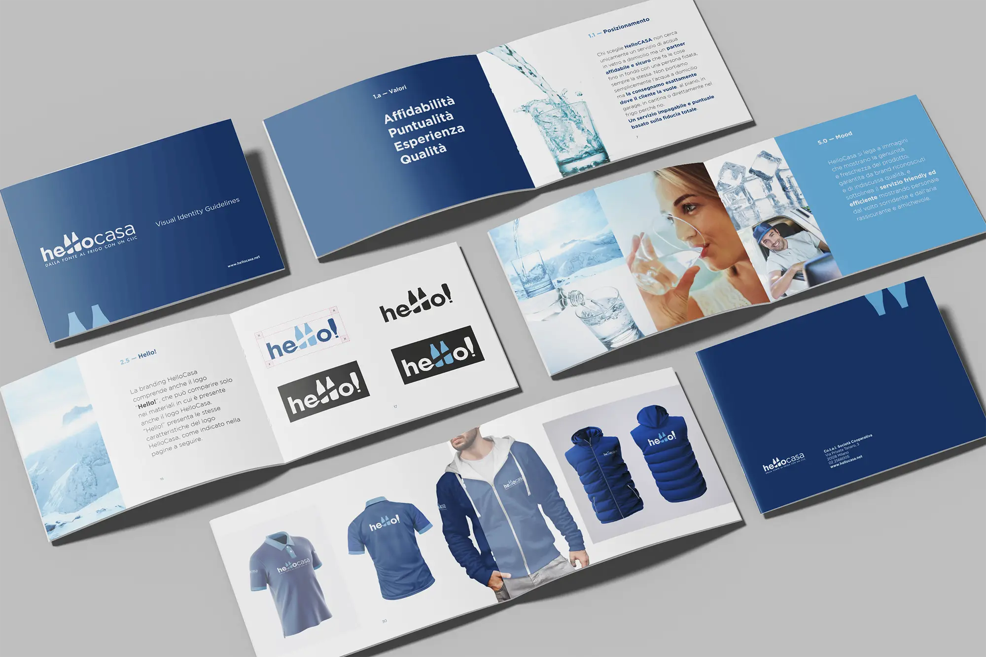 Un set di materiali di branding disposti in diagonale, inclusi un opuscolo con copertina blu scuro, un blocco note e biglietti da visita con un logo.