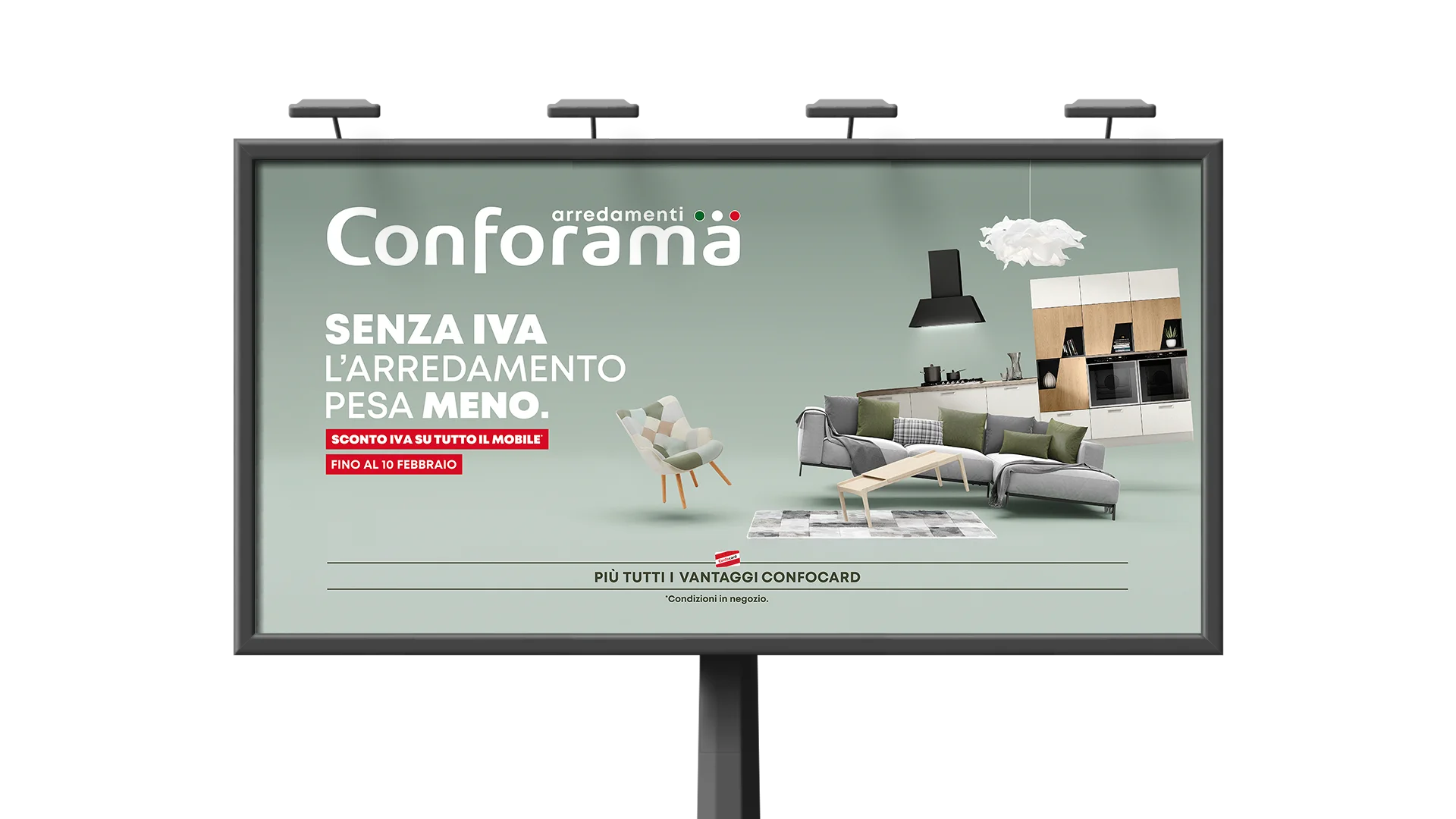 Visual della campagna su affissione di cartellone da esterno Conforama con slogan "Senza IVA l’arredamento pesa meno" su sfondo verde salvia, arredamento moderno con divano grigio, tavolino in legno chiaro e cucina bianca a vista; evidenziato lo sconto IVA su tutti i mobili valido fino al 10 febbraio.